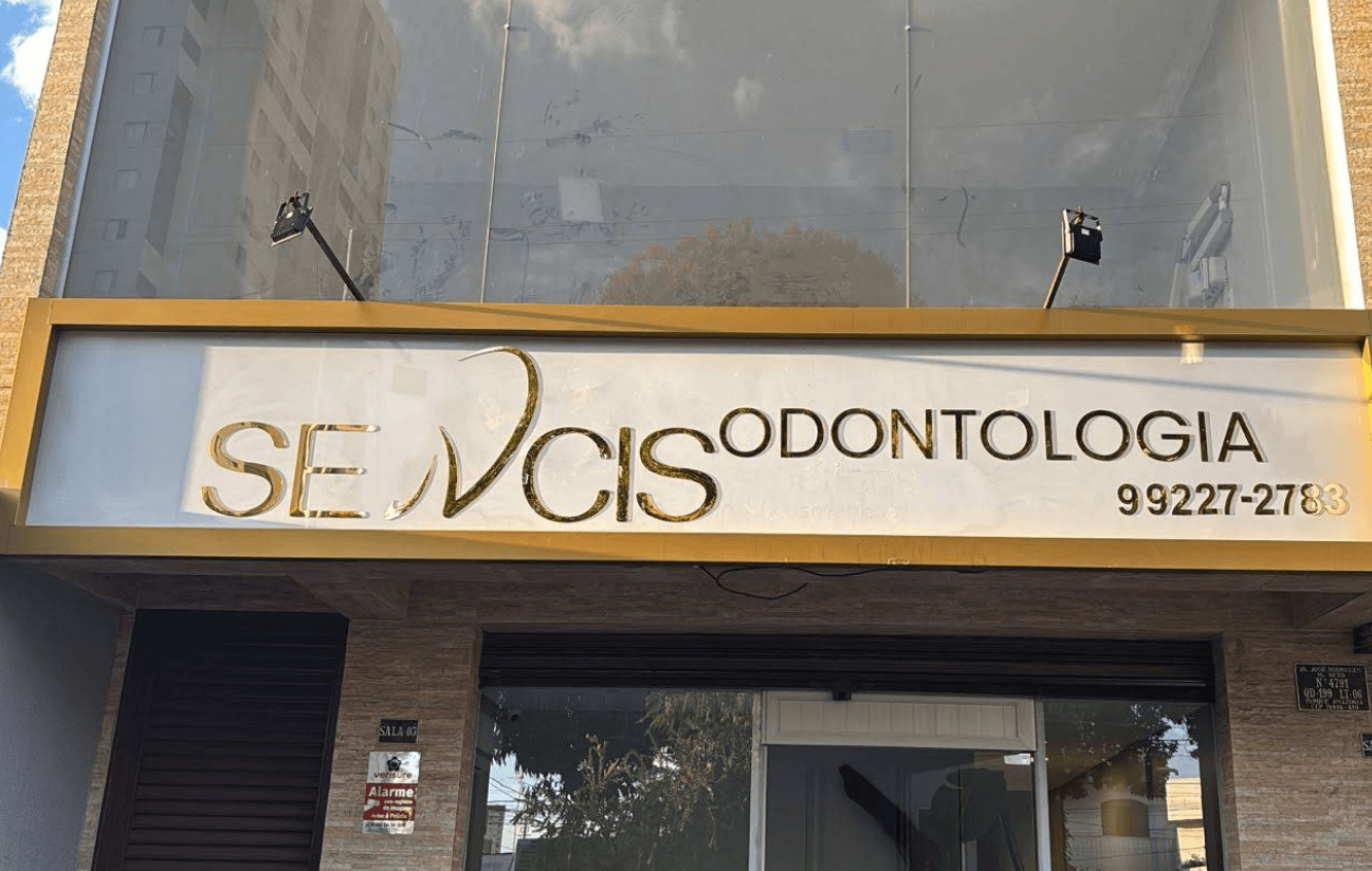 Fachada da Sencis Odontologia com letreiro dourado iluminado sobre a entrada