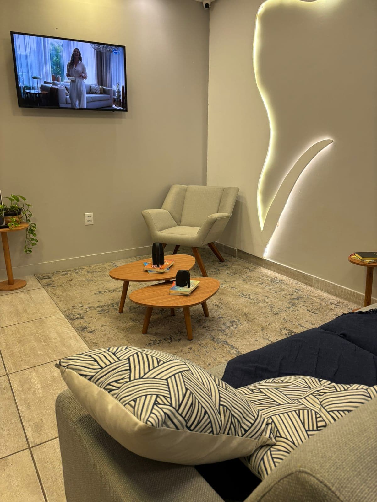 Recepção da Sencis, com poltronas claras, almofadas escuras e iluminação indireta na parede