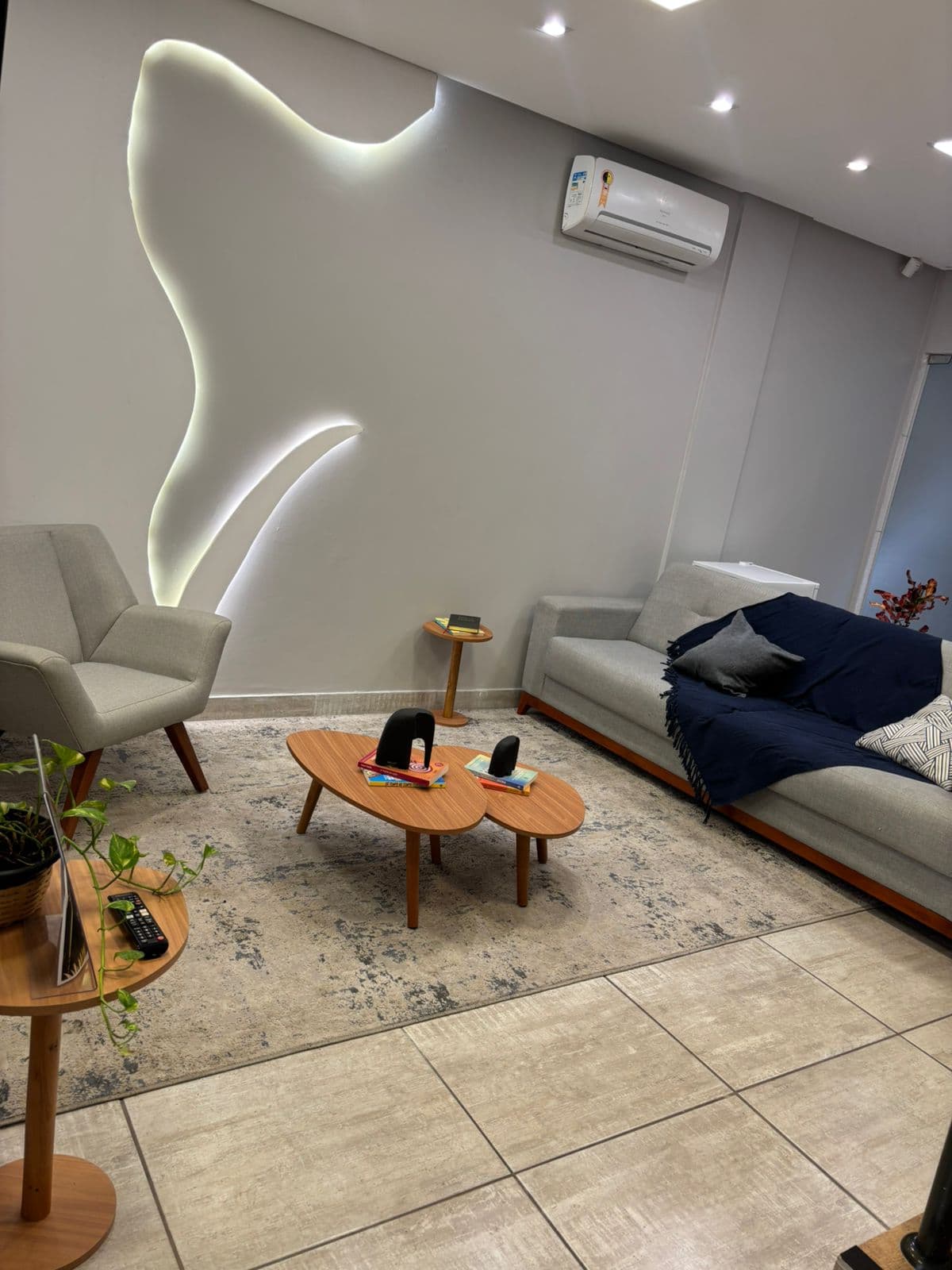 Recepção da Sencis com sofá, poltrona e iluminação indireta